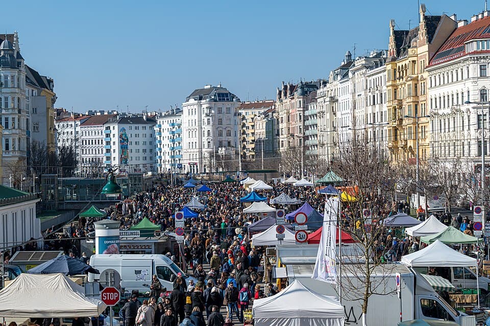 A busy outdoor flea market with crowded stalls and tents