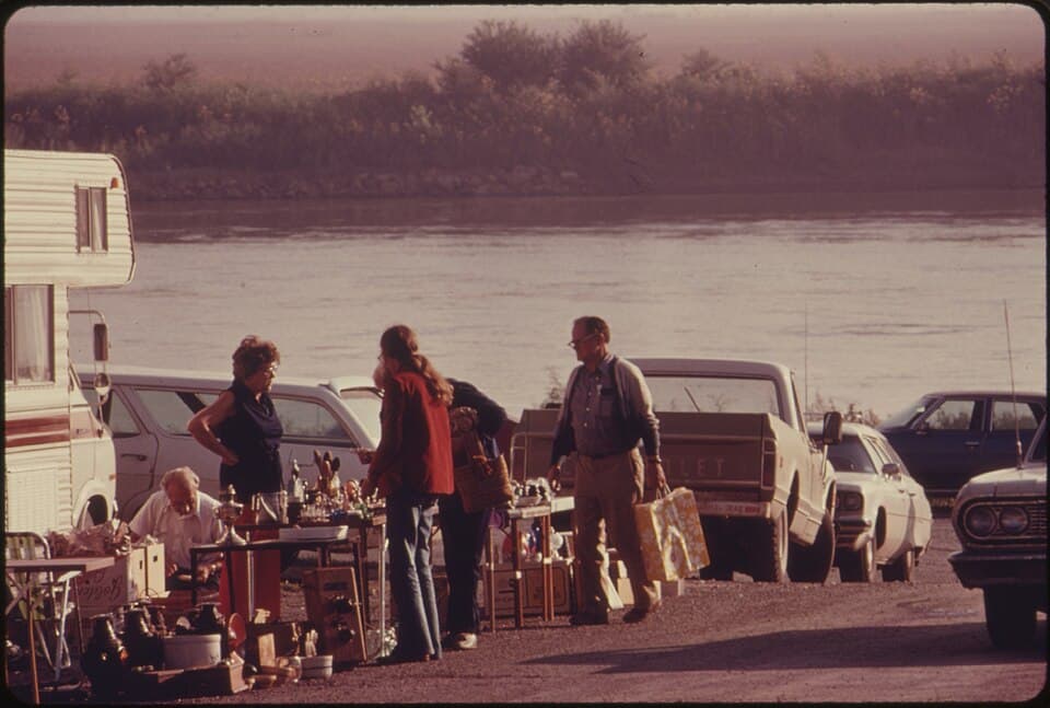 Shoppers browsing tables of goods at an outdoor flea market